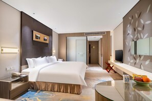 Una habitación de hotel moderna con una cama grande, una mesita de noche y un televisor sobre un soporte.