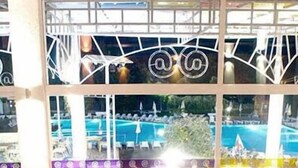 An indoor dining area with multiple tables and chairs, large windows overlooking a pool area. - Com (Balchik)