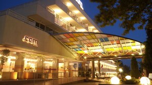 A hotel with a glass facade, a covered entrance, and a sign indicating it is a hotel. - Com (Balchik)