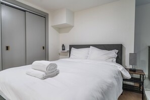 A hotel room with a bed, a nightstand, a lamp, a wall-mounted shelf, and a closet. - Industrial Loft  - Nearby Parking Downtown - 2F (Louisville)