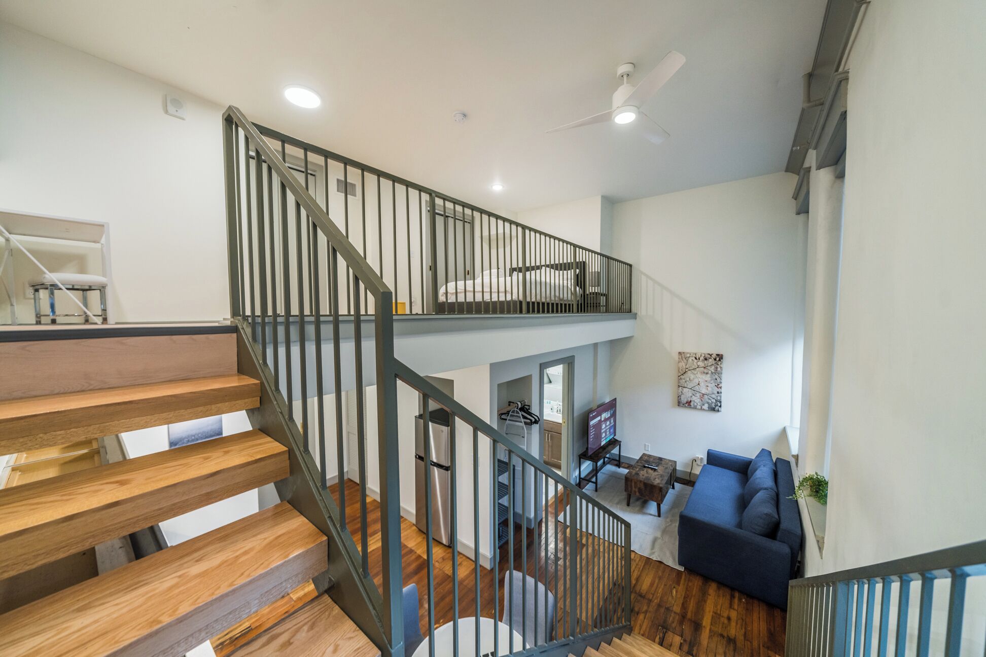 A multi-level interior with a staircase, a living area with a sofa, and a ceiling fan.