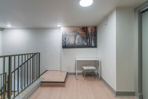 A modern interior with a staircase, a painting of a forest, and a white bench. - Industrial Loft  - Nearby Parking Downtown - 2F (Louisville)