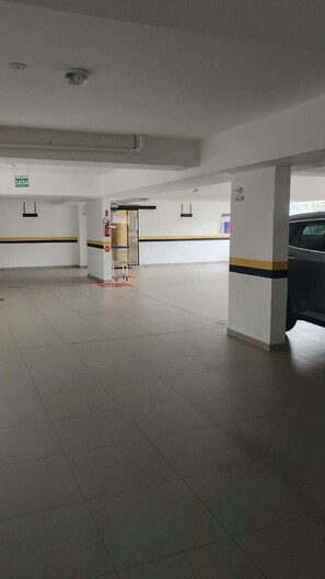 Amplio espacio interior con piso de baldosas, una mesa de recepción y un automóvil cerca.