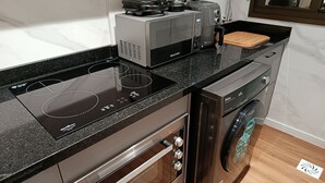 Una cucina moderna con piano cottura a induzione integrato, una macchina da caffè, un tostapane e una lavatrice.