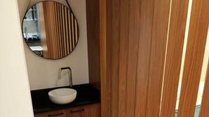 Un bagno moderno con un mobile bagno in legno, uno specchio rotondo e un lavandino bianco.
