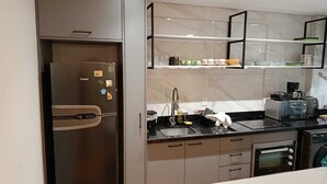 Una cucina moderna con frigorifero integrato, macchina da caffè e forno a microonde.