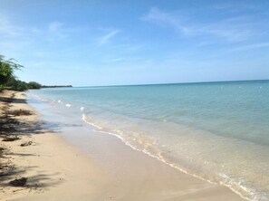 A beach with clear water, sandy shore, and sparse vegetation. - Delightful 2-bedroom apartment with AC in charming Combate (Combate)