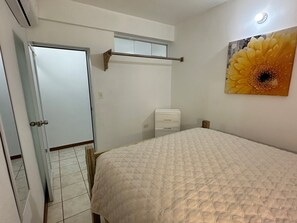 Ein Schlafzimmer mit einem Bett, einer Tür, einer Wand-Klimaanlage und einem Blumenbild.