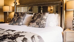 Une chambre d’hôtel avec un grand lit, deux lampes de chevet, une table de chevet et un miroir au-dessus du lit.
