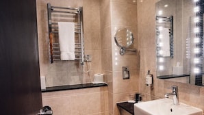 Une salle de bain moderne équipée d’un lavabo, d’un miroir, d’un porte-serviettes et de toilettes.
