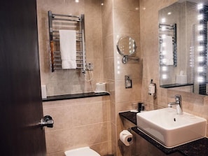 Un baño moderno con lavamanos, espejo, toallero y retrete.