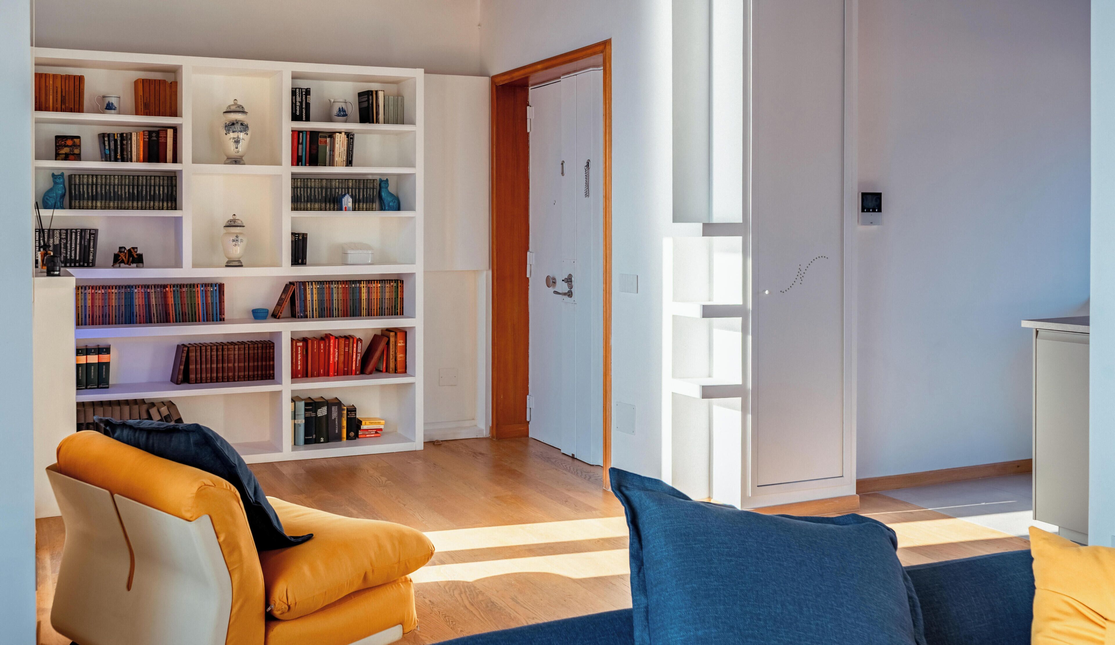 Un salon moderne avec une bibliothèque, un canapé et une porte donnant sur une autre pièce.