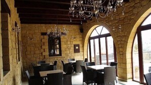 A restaurant with stone walls, arched windows, and black wicker furniture. - Palazzo Loupassi Boutique Hotel (Platanias)
