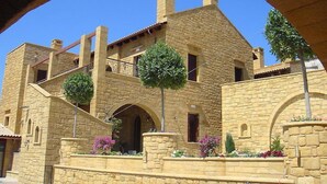 A stone building with a balcony, arched windows, and a central archway. - Palazzo Loupassi Boutique Hotel (Platanias)