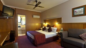 A hotel room with a bed, a sofa, a TV, a ceiling fan, and a bathroom visible through an open door. - Best Western Early Australian (Mildura)