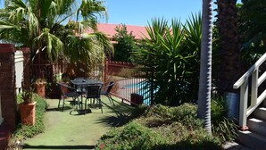 A patio with a table and chairs, surrounded by a fence and various plants. - Best Western Early Australian (Mildura)