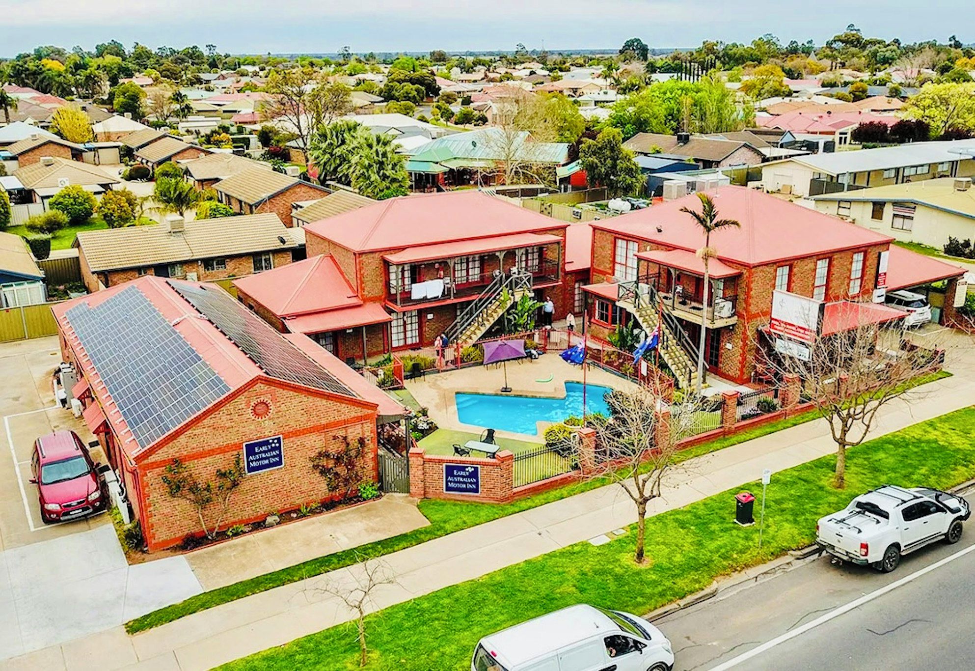 Una posada de dos pisos con piscina, rodeada de casas unifamiliares.