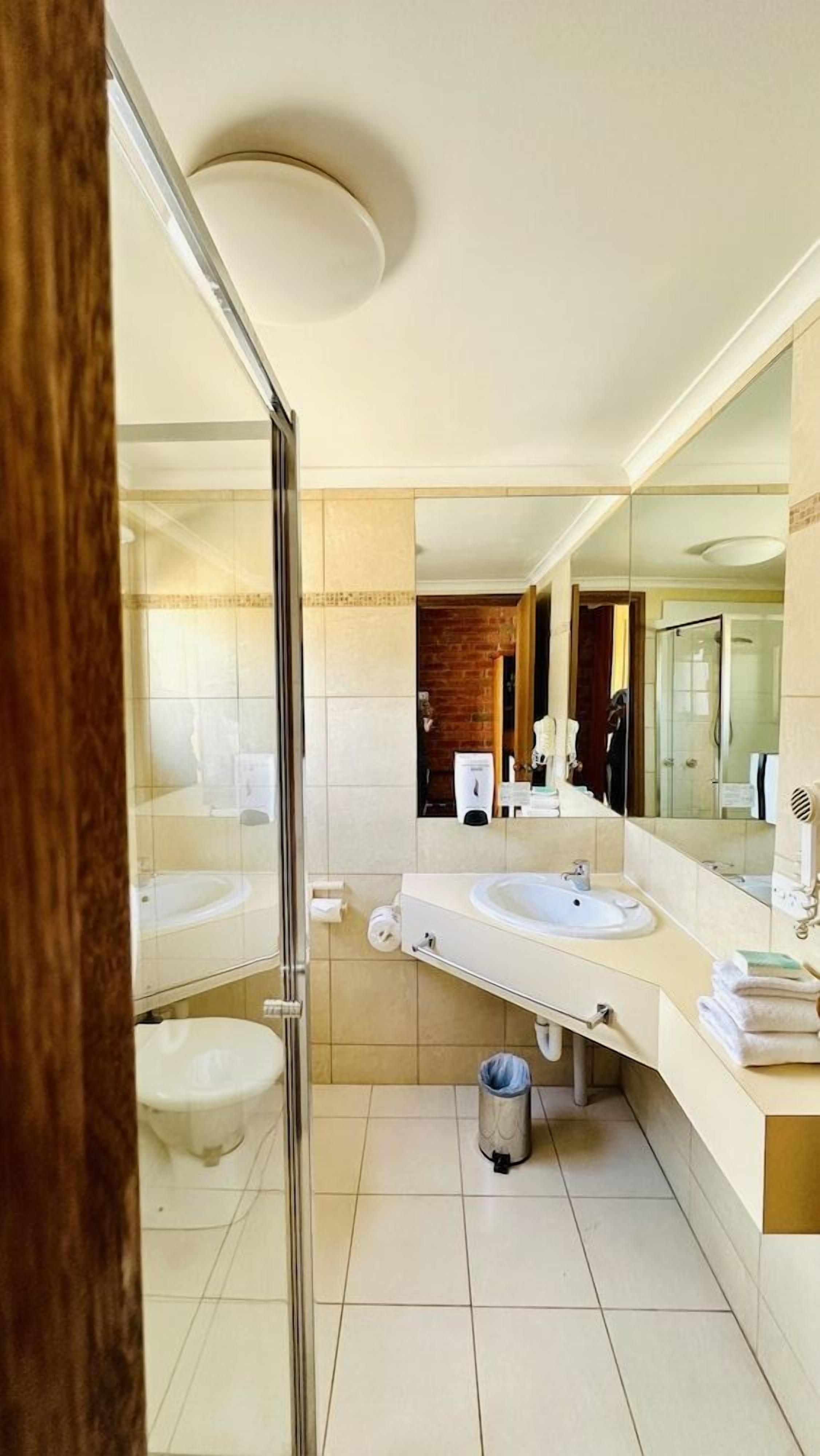 Un baño moderno con dos lavamanos, cabina de ducha con mampara de vidrio y un espejo grande.