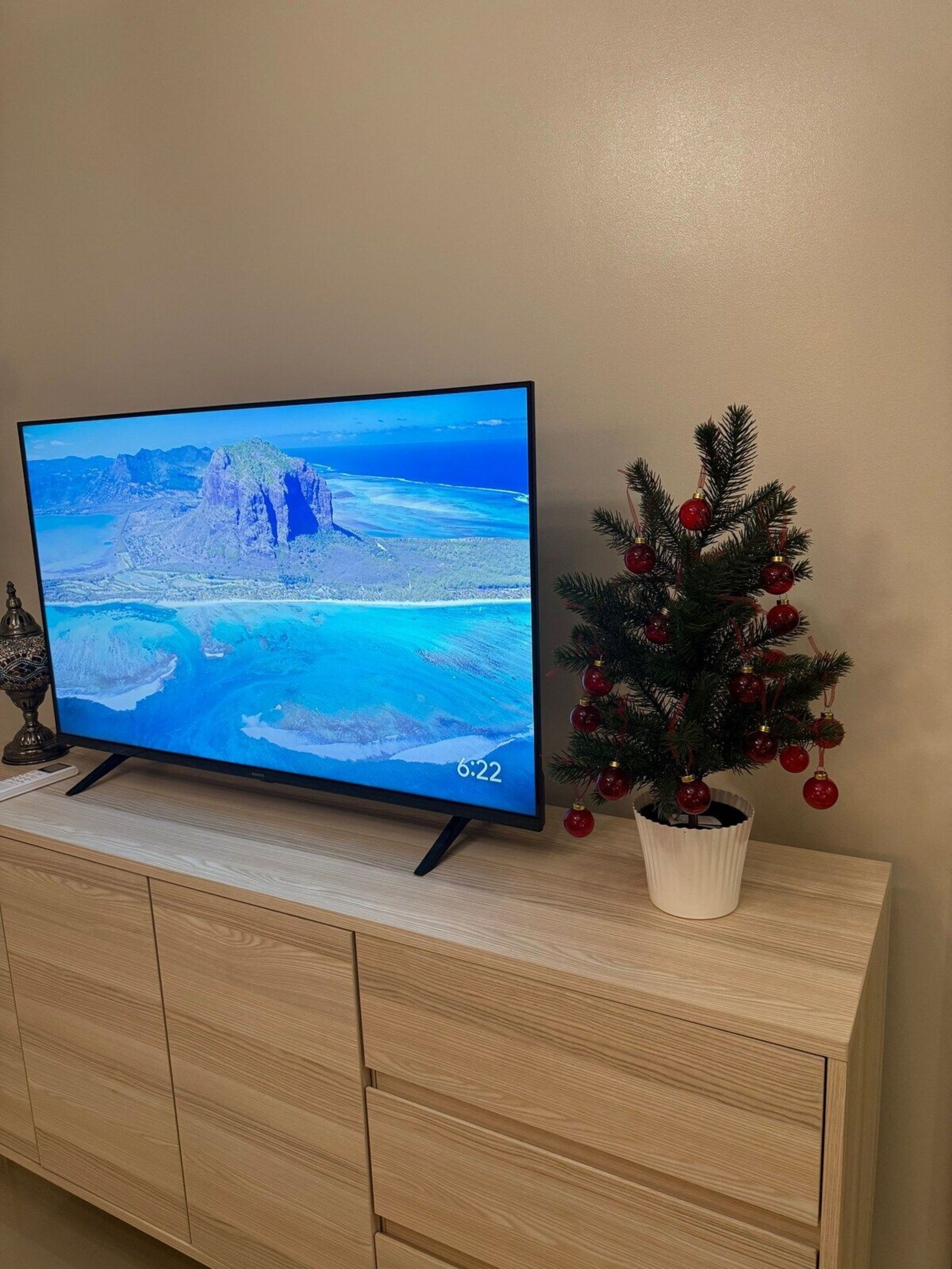 Ein Fernseher auf einer Holzkommode, neben ihm ein Weihnachtsbaum.