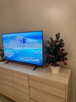 Un televisor sobre un mueble de madera, con un árbol de Navidad a su lado.