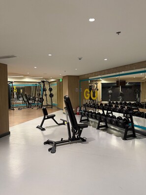 Un gimnasio con equipo de levantamiento de pesas, un espejo y una pared con mensajes motivacionales.