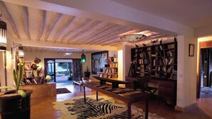 Un amplio espacio de estar con una gran mesa de madera, un alfombra estampado con diseño de cebra y una estantería llena de libros.