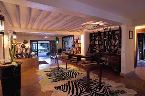 A spacious living area with a large wooden table, a zebra-patterned rug, and a bookshelf filled with books.