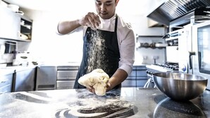 Una persona en una cocina espolvoreando harina sobre una superficie.