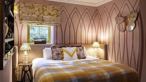 Un dormitorio con cama, dos lámparas de noche, una ventana con vistas y un panel decorativo en la pared.