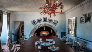 Un comedor con una mesa larga, sillas, una chimenea y un candelabro único.