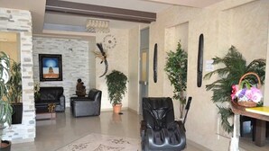A spacious living area with a black leather sofa, a massage chair, and a large potted plant. - DND Villa Hotel (Niš)