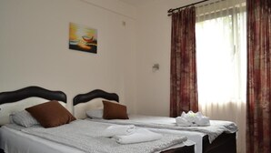 A hotel room with two beds, a painting on the wall, and a window with curtains. - DND Villa Hotel (Niš)