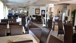 A hotel dining area with tables and chairs, a bar, and a reception desk. - DND Villa Hotel (Niš)