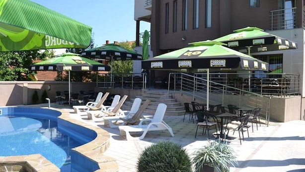 A pool area with lounge chairs and umbrellas, a staircase, and a building with balconies. - DND Villa Hotel (Niš)