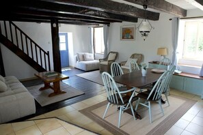 Ein Essbereich mit einem Holztisch, weißen Stühlen, einer Couch und einer Treppe.