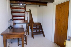 A room with a wooden desk, a chair, a ladder, and a staircase. - Storybook Stone Cottage with Private Garden (Oradour-sur-Vayres)