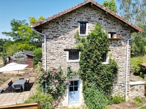 A stone house with a blue door, a small window, and a garden with a patio. - Storybook Stone Cottage with Private Garden (Oradour-sur-Vayres)