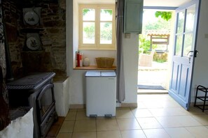 Una cucina compatta con un fornello vintage, un piccolo frigorifero e una finestra vista verde.