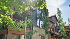 A multi-story building with stone and wood exterior, large windows, and a balcony. - Abode at The Timbers, minutes to skiing, hot tub (Ketchum)