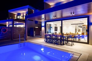 A modern outdoor pool area with a dining setup. - Kamelia Luxury Villa 2 (Crete)