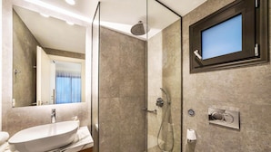 Une salle de bain moderne avec une douche à parois de verre, un grand miroir, un lavabo et des toilettes.
