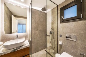 A modern bathroom with a glass-enclosed shower, a large mirror, a sink, and a toilet. - Kamelia Luxury Villa 2 (Crete)