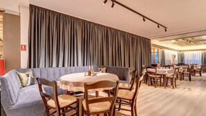 A dining area with a round table, chairs, and a sofa. - Murgavets Hotel (Chepelare)