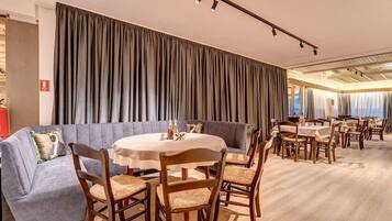 A dining area with a round table, chairs, and a sofa.