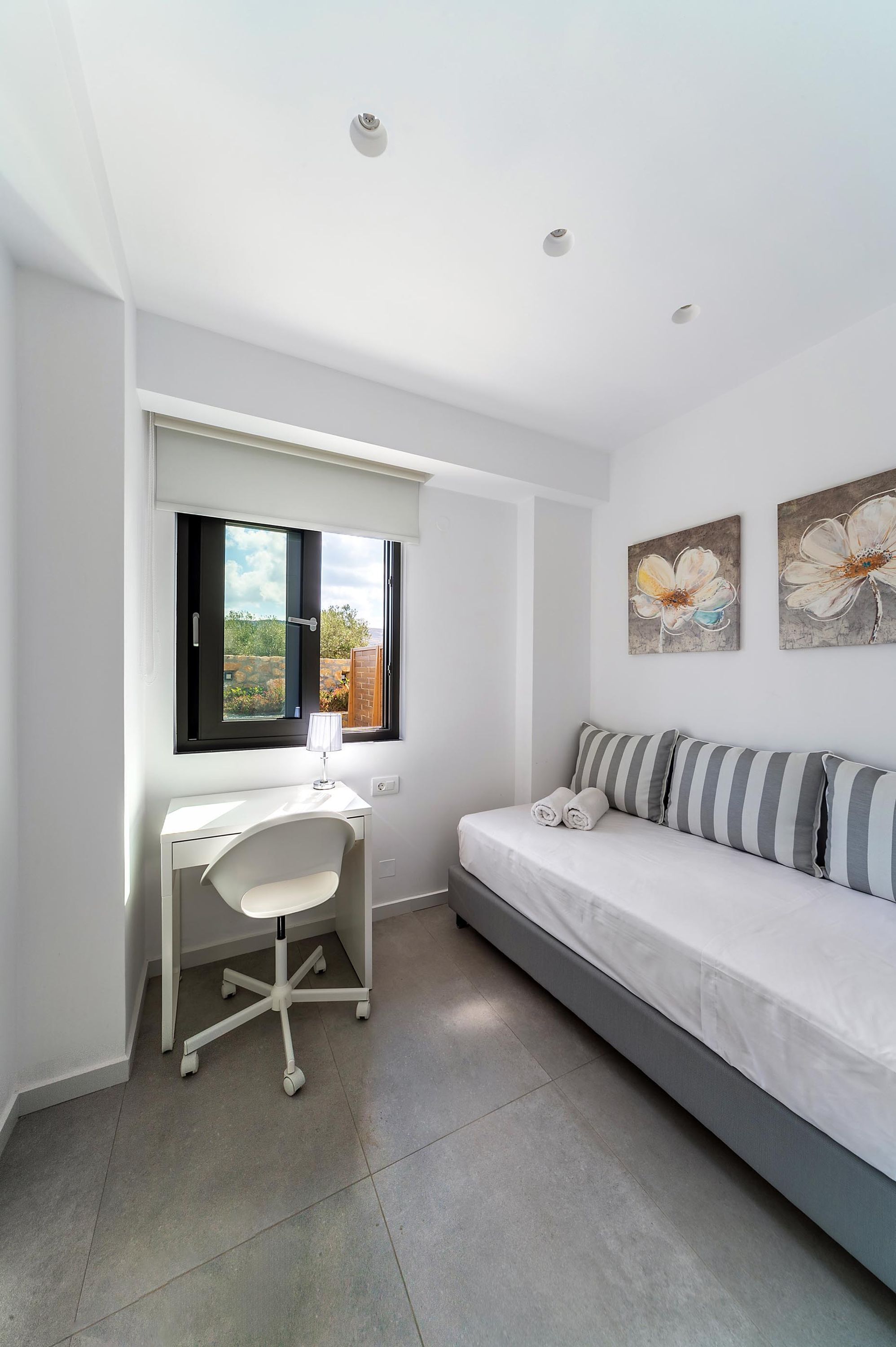 A bedroom with a bed, a desk, and a window.