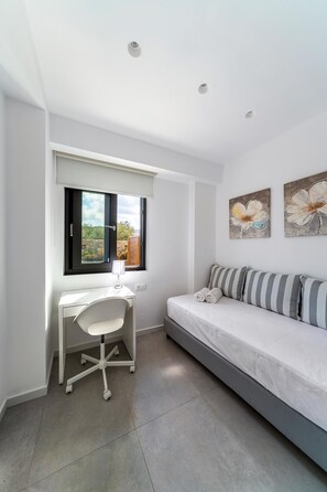 Un dormitorio con cama, escritorio y ventana.