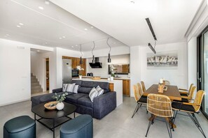 Un espace de vie moderne comprenant un canapé, une table à manger et des chaises, un coin cuisine et un escalier menant à un autre niveau.