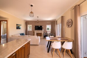 A modern living room with a sofa, TV, fireplace, and dining area with chairs. - Villa Melody in Zakynthos (Zakynthos)