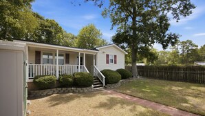 A single-story house with a front porch, a small staircase leading to the entrance, and a well-maintained lawn. - Cozy Holden Beach dog friendly beach cottage. Only 1.4 miles to Holden Beach on mainland side. (Supply)