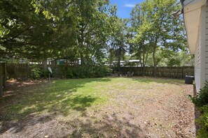 A backyard with a wooden fence, a satellite dish, and a grassy area. - Cozy Holden Beach dog friendly beach cottage. Only 1.4 miles to Holden Beach on mainland side. (Supply)